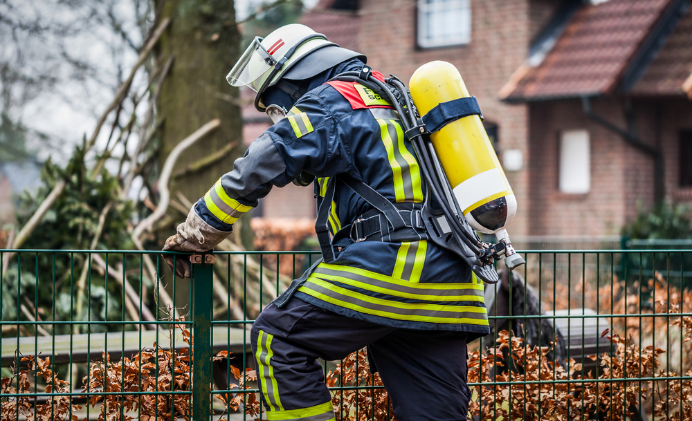 Firefighter outdoor in action and climbing with oxygen bottle and mask