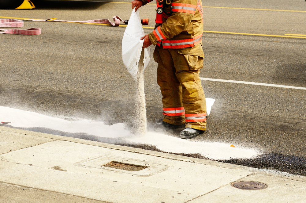 Fire fighters spreading absorbant on chemical spill on road