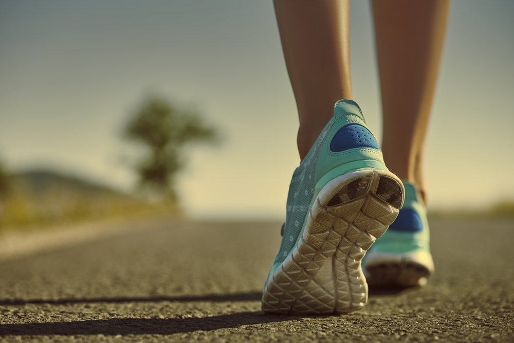 Closeup of athlete female feet in running shoes jogging on the road early in the morning