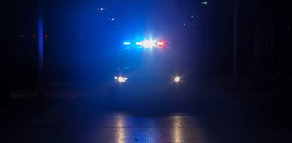 Police car with their lights on flashing red and blue at night