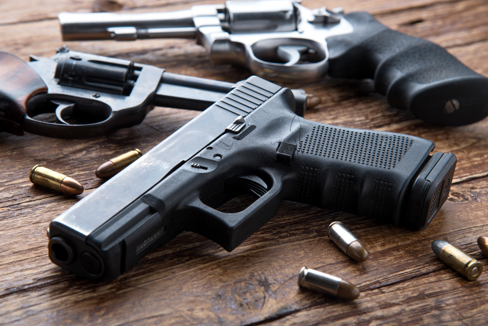 Gun with ammunition on wooden background