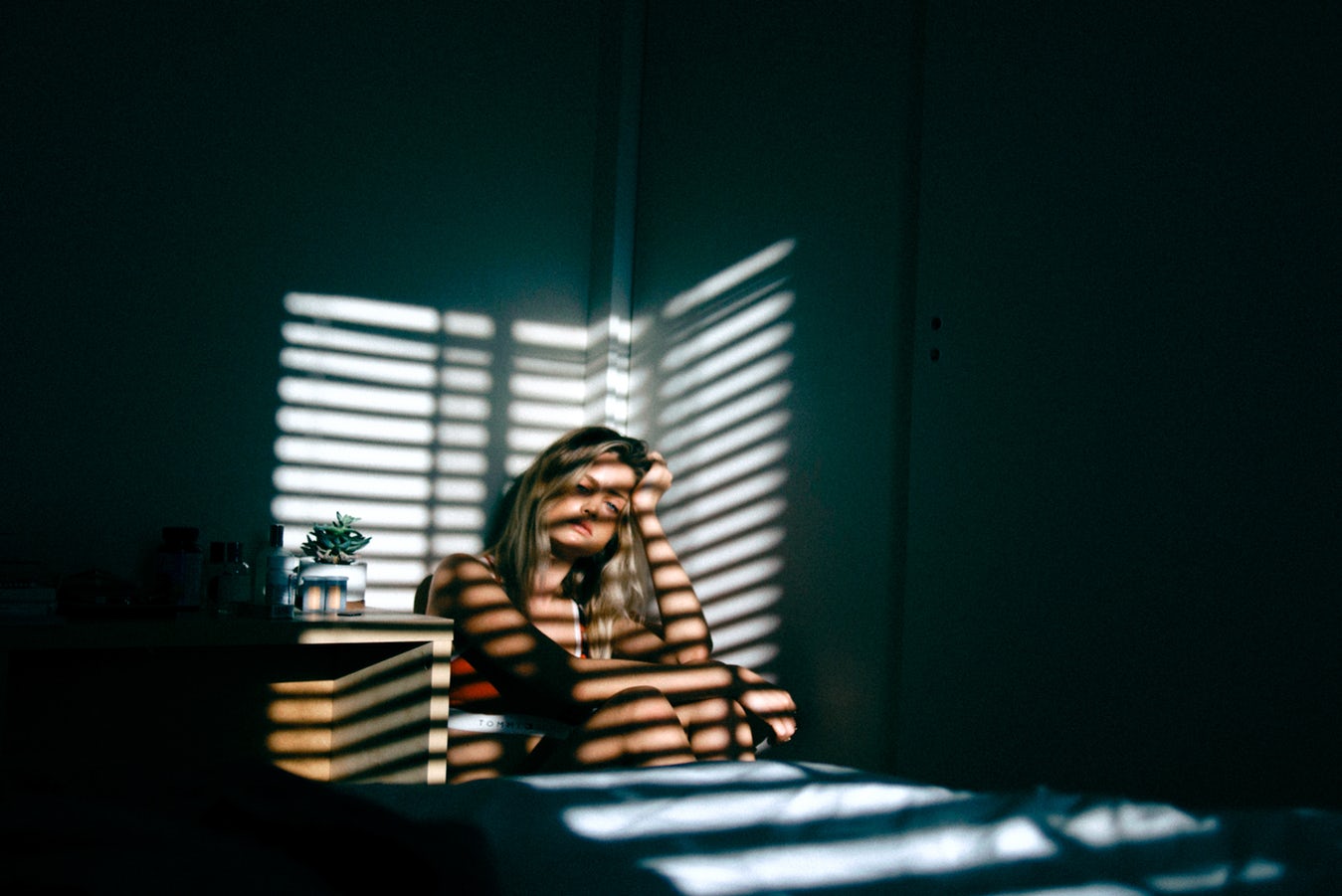 woman sitting in corner of room, lamenting