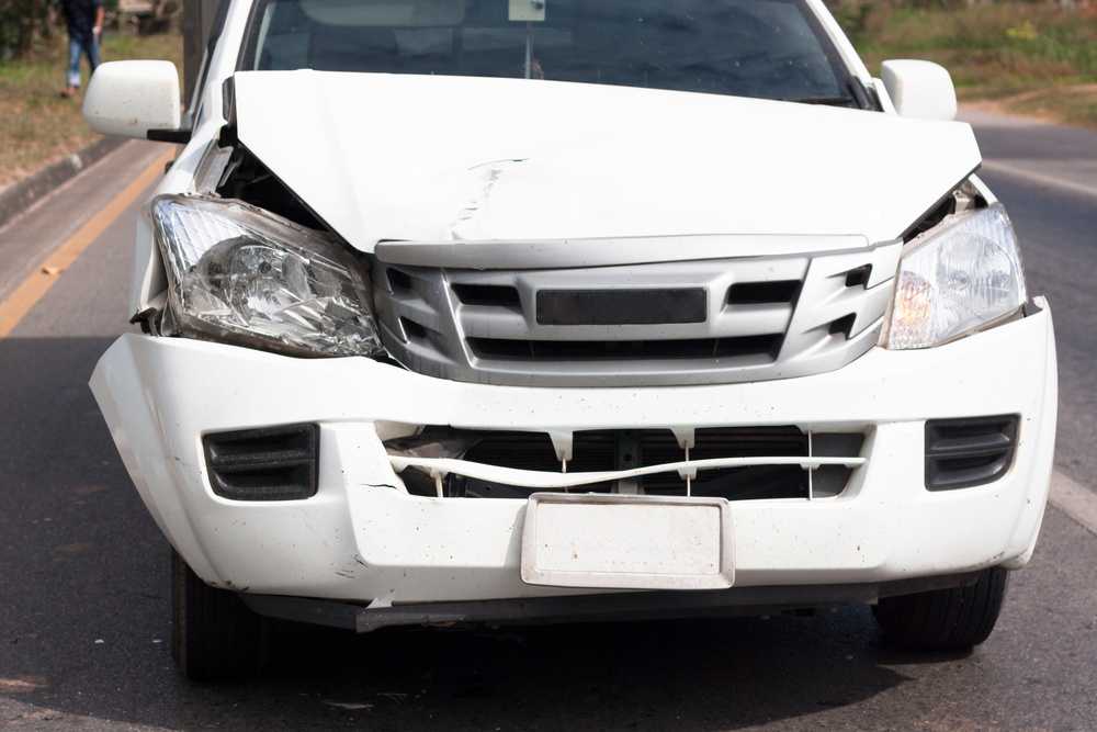 Front of a white pickup trucks were damaged in an accident on the road