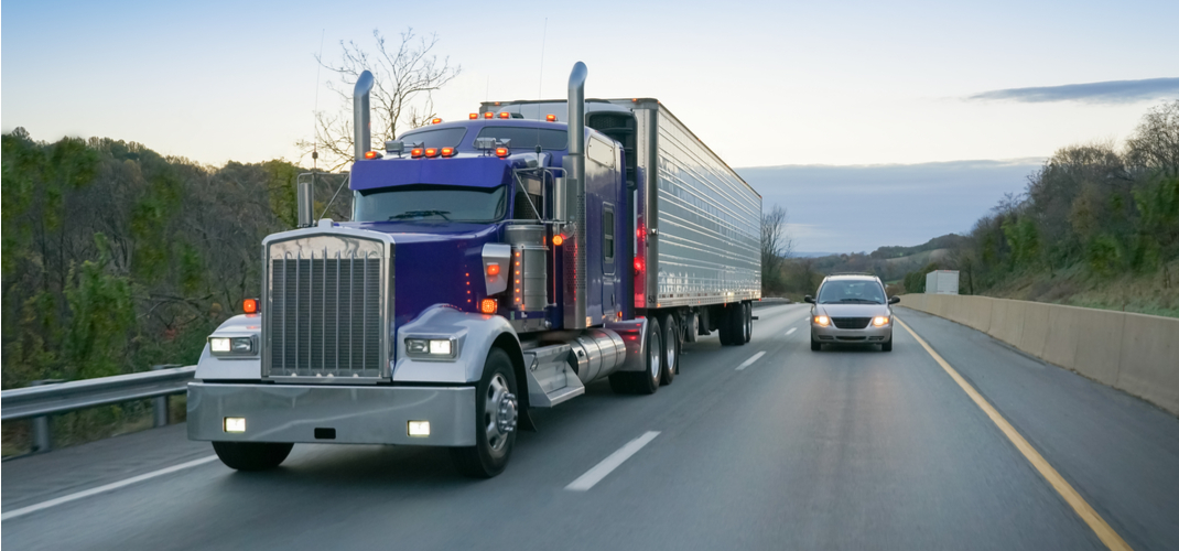 Car sharing the road with a semi truck on the highway