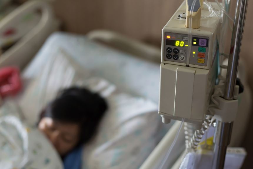 Patient asleep in hospital bed. Heart monitor in focus.
