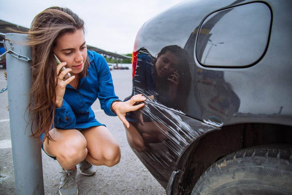 woman examining her car after an accident