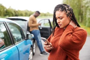 who can you sue in a car accident, woman on phone at car accident scene