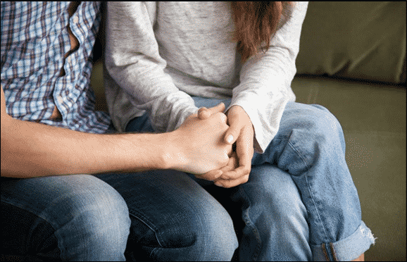 man and woman holding hands, comforting each other